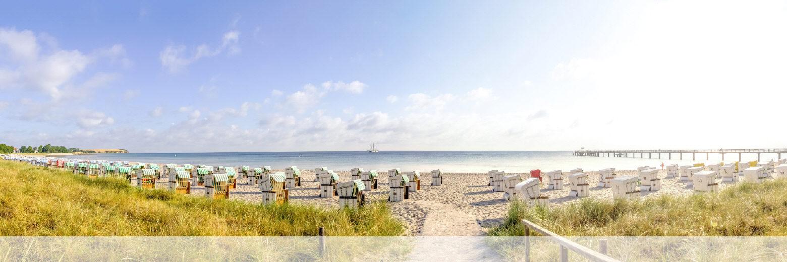 Ostseebucht mit vielen Strandkörben und einer Seebrücke